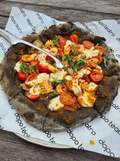 A freshly prepared pizza sits atop a white paper plate on a wooden picnic table, ready to be enjoyed