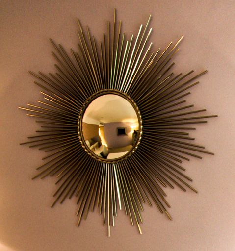 A closeup shot of a golden sun design hotel room mirror