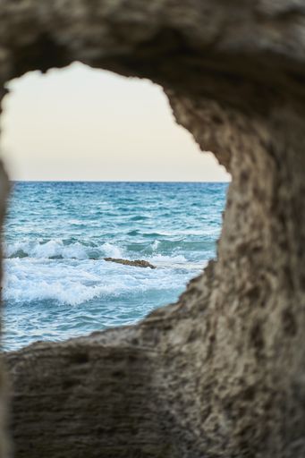 A scenic shot of horizon across the ocean with turquoise water framed by a rocky cliff