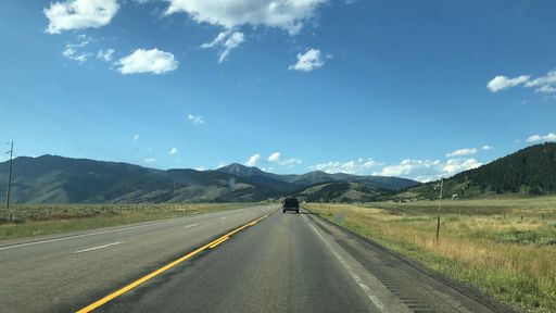 This image features a stunning panoramic view of a mountain range, with a winding road snaking through its undulating landscape