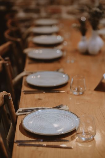 An elegant table setting with white plates and glasses on a wooden table in the restaurant