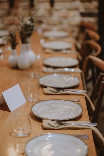 An elegant table setting with white plates and glasses on a wood table of the restaurant