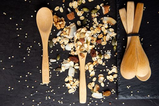 A top view of healthy and delicious muesli with wooden spoons on a black background