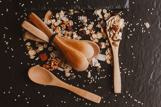 A top view of healthy and delicious muesli with wooden spoons on a black background