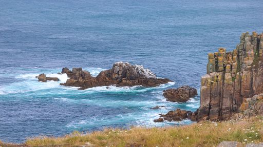 A beautiful, tranquil scene of a rocky shoreline with bright blue ocean waters in the background