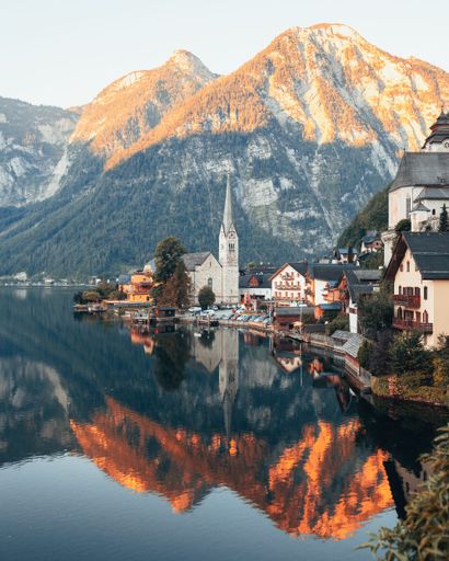 The Hallstatt tranquil town situated beside a lake surrounded by majestic mountains during a stunning sunset