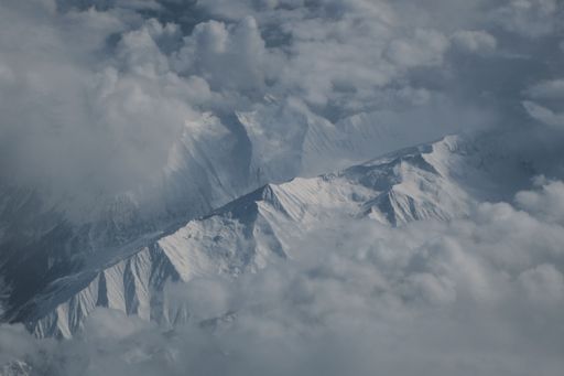 An aerial view of the snow covered Hindu Kush mountain range covered in fluffy white clouds