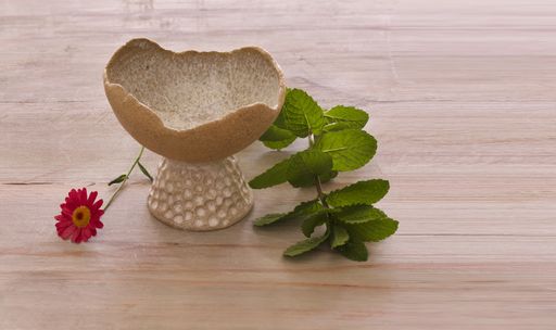 A clay fruit vase and a flower on a wooden table