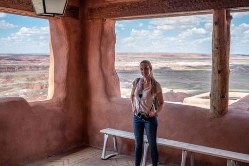 Portrait of a young tourist girl with photo camera on the porch of the old indigenous house in Petrified Forest National Park