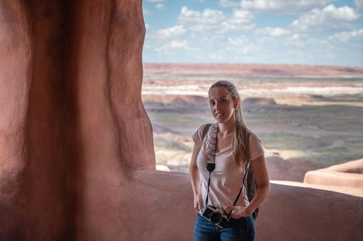 Portrait of a young tourist girl with photo camera on the porch of the old indigenous house in Petrified Forest National Park
