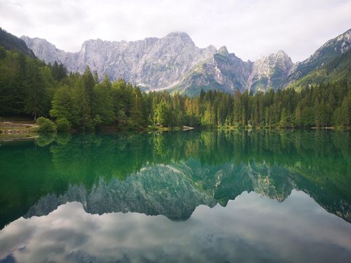 A green lake in the middle of a mountain range with some trees on each side
