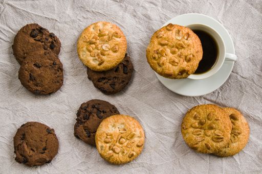 A cup of black espresso coffee and cookies on the white cloth background, morning food, and drink, sweet pastry dessert with chocolate and nuts