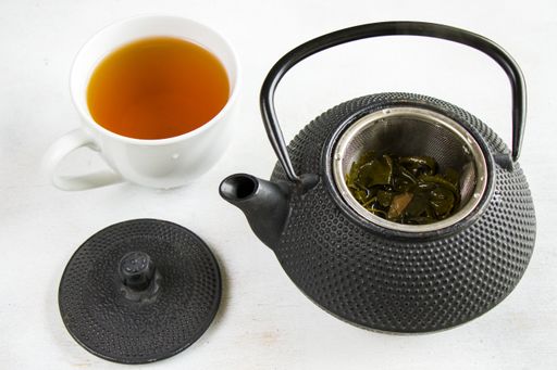 A herbal tea, iron teapot and cup of tea on the white background, chinese traditional tea serving