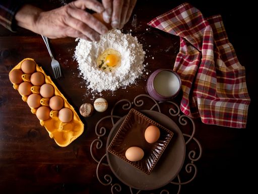 A person preparing a meal at a kitchen table with eggs