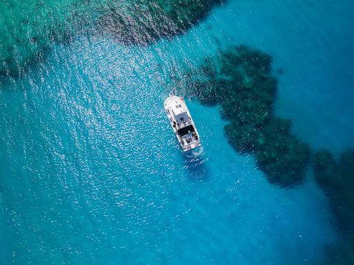 An aerial view of a white boat on a clear, blue water on a sunny day