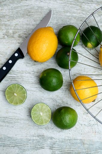 A vertical shot of fresh lemons and limes on a wooden surface