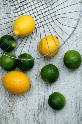 A vertical shot of fresh lemons and limes on a wooden surface