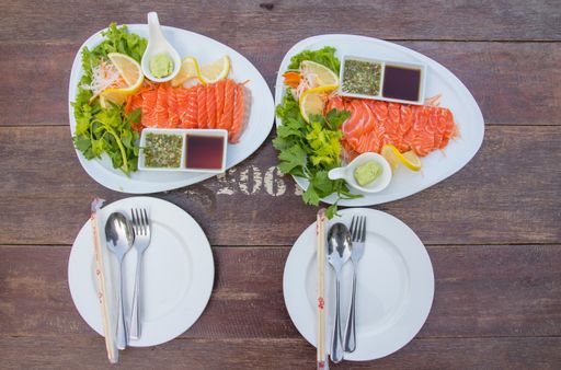 A top view of Japanese Sashimi with fresh vegetables and sauce on a wooden table