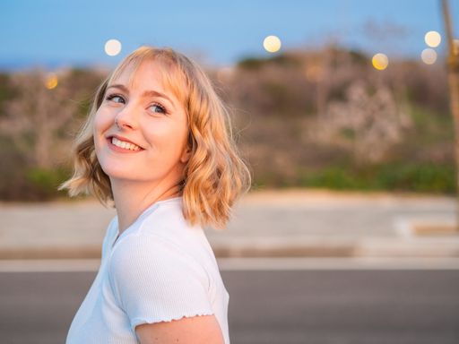 A shallow focus of a blond Caucasian woman with a nose ring posing at a street against bokeh street lights