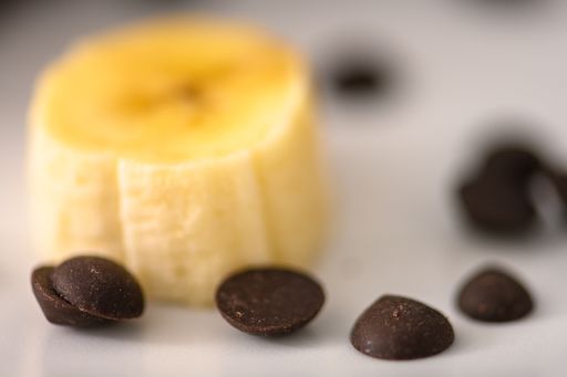 A selective focus of chocolate chips beside a sliced banana on a white plate
