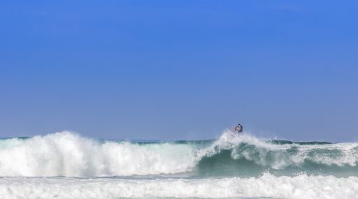 A surfer on a powerful wave under the clear blue sky