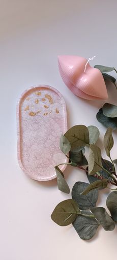 A pink lip-shaped candle resting on a white and pink abstract background