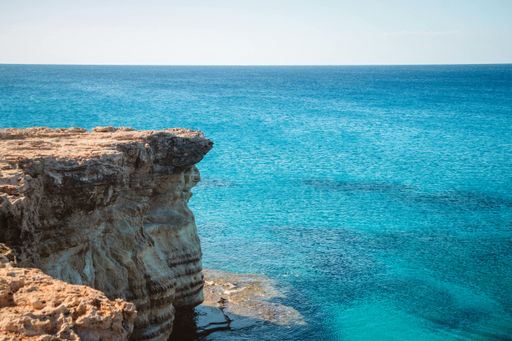 A wide angle shot of a cliff next to the ocean during daytime