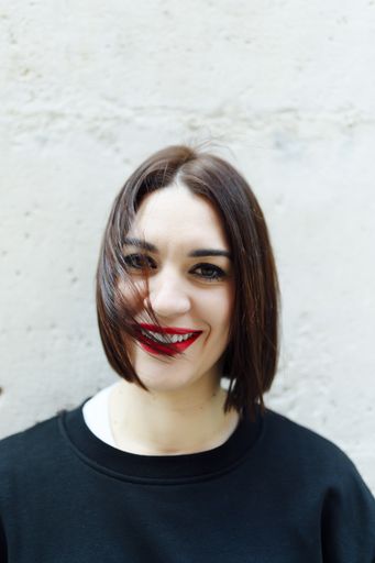 A portrait of a cheerful Spanish female with a bob style haircut and red lipstick