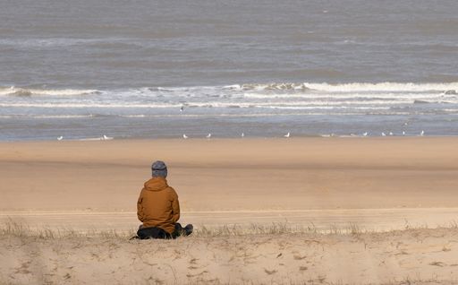 A man sitting alone on a shore and enjoying the beautiful ocean view