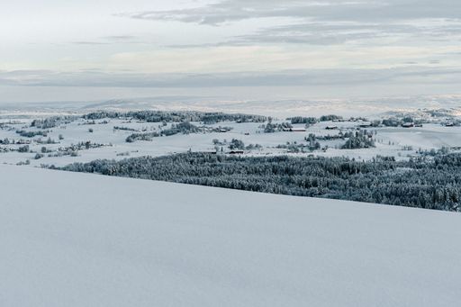 A beautiful shot of a town covered in snow in a mountain range in Toten, Norway