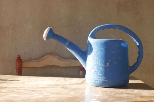 A blue watering can on a wooden table