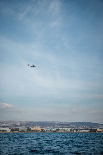 A vertical shot of an airplane flying over the ocean