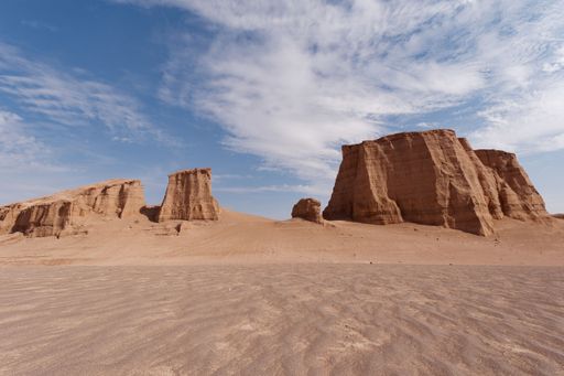 A breathtaking desert landscape featuring tall, red-hued rock formations against a bright blue sky