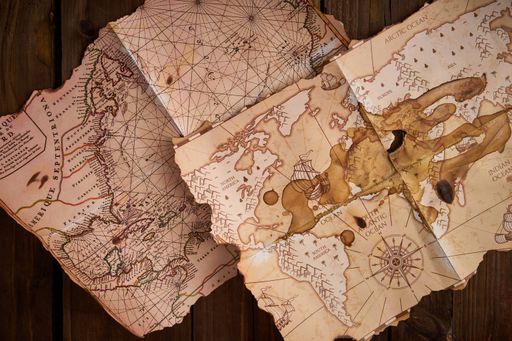 A closeup shot of antique maps on a wooden table.