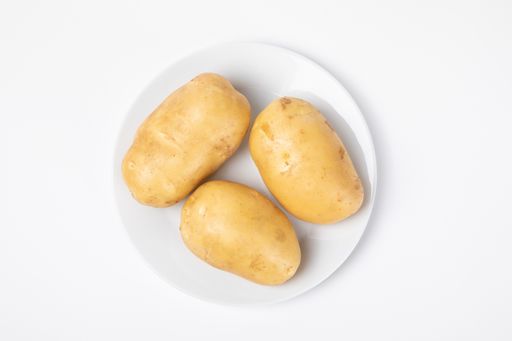 A top view of raw potatoes on the plate isolated on white background