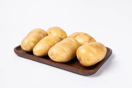 The fresh raw potatoes on a wooden tray isolated on white background