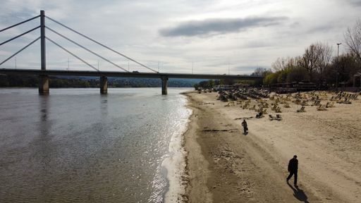 A tranquil beach scene featuring a beach close to the shoreline with a bridge visible in the background