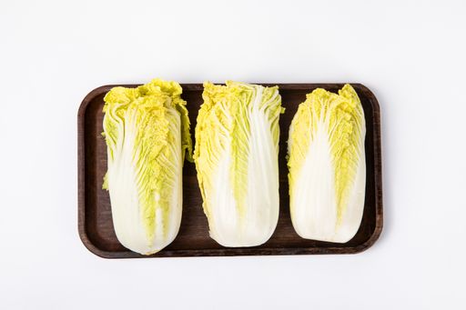 A top view of fresh chinese cabbage ​on a wooden tray isolated on white background