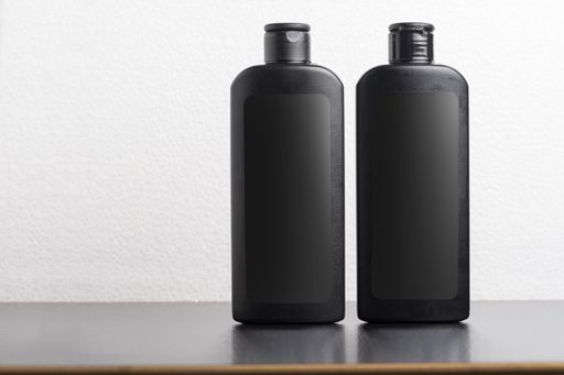Two black hair shampoo bottles in front of a light gray background, editable mock-up series template ready for your design