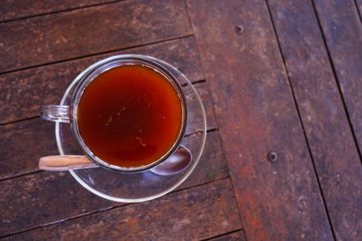 A top view of a cup of black tea on the wooden surface