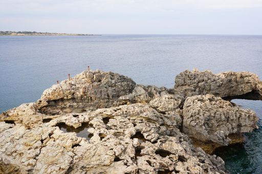 The mesmerizing view of the cliff on the shore of an ocean under the blue sky