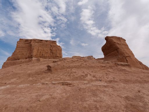 A breathtaking desert landscape featuring tall, red-hued rock formations against a cloudy sky