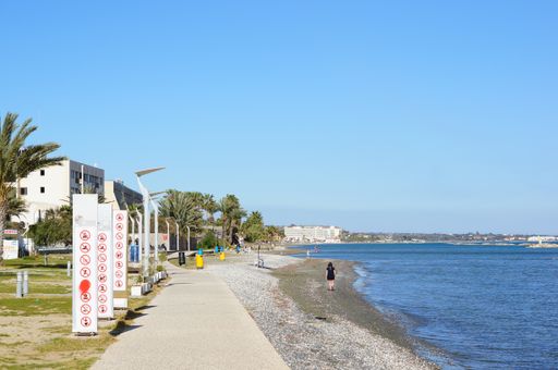 Footpath along the sea with hotels and warning signs.