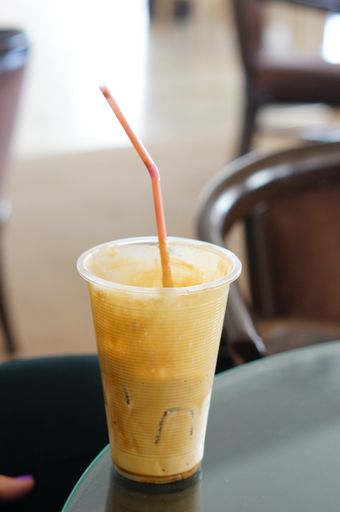 A vertical shot of a coffee with ice and a straw