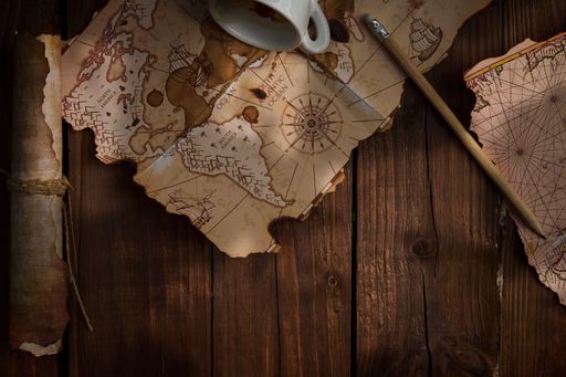 A top view of an antique world map with a cup of coffee next to it and plenty of copy space