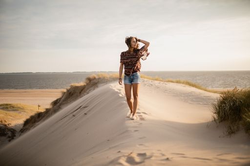 A wide angle shot of a woman walking on the sand during daytime