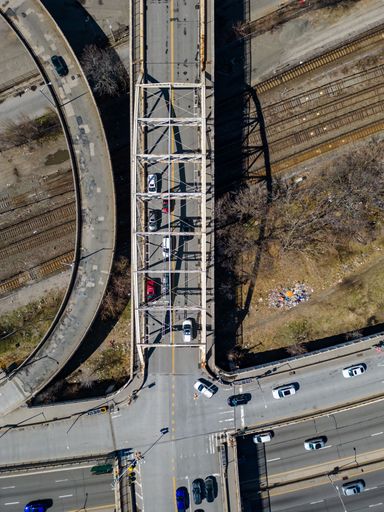 An aerial view of a bustling cityscape featuring a bridge, with multiple lanes of traffic snaking through the landscape below