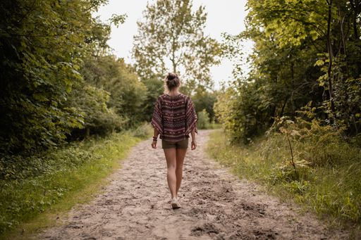 A wide angle shot of a woman walking through a walkway surrounded by trees