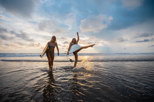 A wide angle shot of two women standing on the beach during a sunset