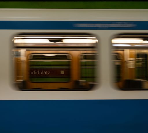 A close-up of a train arriving at a Munich subway station in Germany with a blurred effect, emphasizing the sense of motion